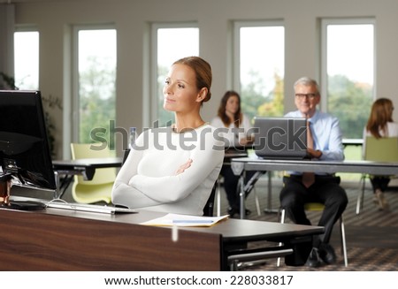 Portrait of mature business woman sitting in front of computer while thinking on problem.