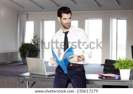 Young sales man holding files in hands and sitting at office. Business people.