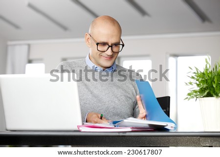 Portrait of chief financial officer analyzing data on laptop, while sitting at office.  Business people.