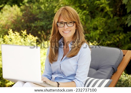 Portrait of busy sales woman working on laptop while sitting at home in garden.