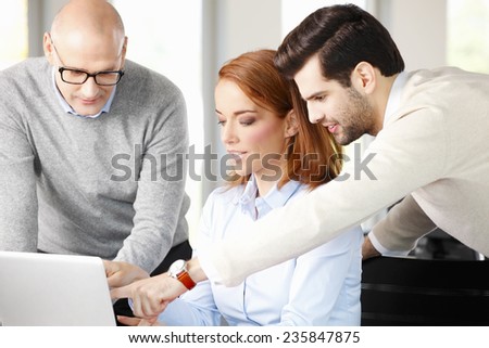 Sales team working on project while sitting at meeting in front of computer.