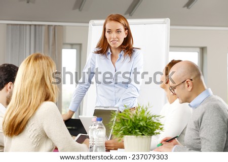 Portrait of efficiency business woman presenting project to business team while sitting at meeting.