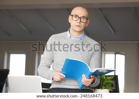 Portrait of financial leader holding files in hands and working on cash-flow forecast.
