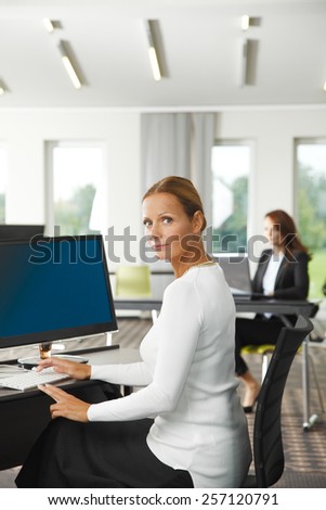 Portrait of successful business woman sitting at office in front of computer.
