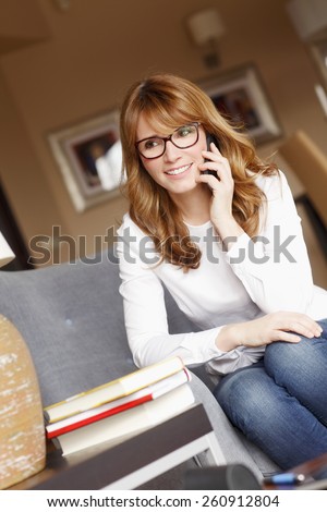 Portrait of interior designer woman making a call while sitting at sofa at her studio. Designer studio owner.