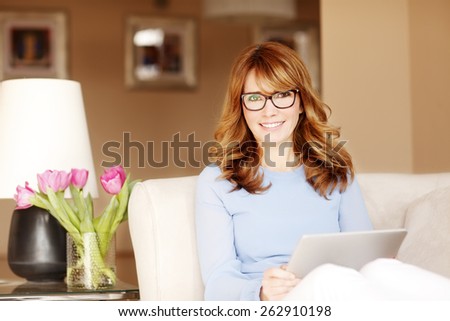 Portrait of smiling busy business woman working at home with digital tablet while sitting at sofa. Small business.