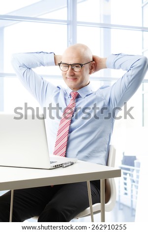 Portrait of smiling businessman sit back while sitting in front of laptop at office. Business people.