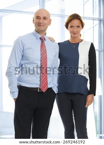 Portrait of sales team standing at office while looking at camera and smiling.