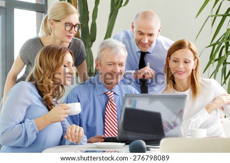 Image of business people working at office. Busy businesswomen and businessmen sitting at conference desk in front of laptop and working on financial plan.