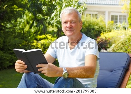 Portrait of senior people sitting at sunbed at home and reading book.  Old man relaxing at garden.