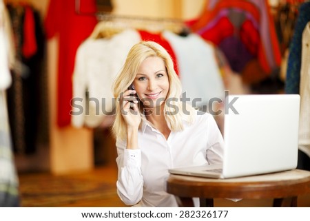 Small vintage store owner. She is using her telephone and laptop to take orders for her store.
