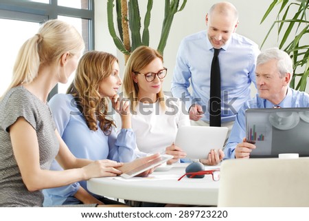 Portrait of attractive businesswoman presenting her idea to team. Business people sitting around conference table and using digital tablet while consulting and working on business presentation.