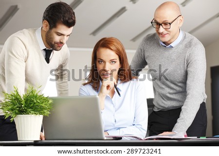 Portrait of executive businesswoman sitting in front of computer with sales men and working on new project.