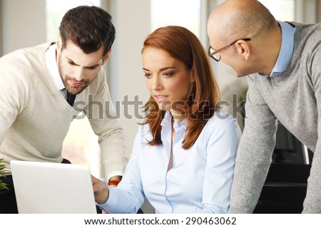 Portrait of executive businesswoman sitting in front of computer with sales men and working on new project.