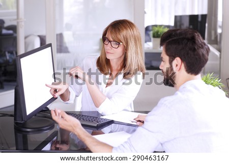 Portrait of investment advisor advise to young businessman to start small business. Middle age professional woman points out to the computer screen.
