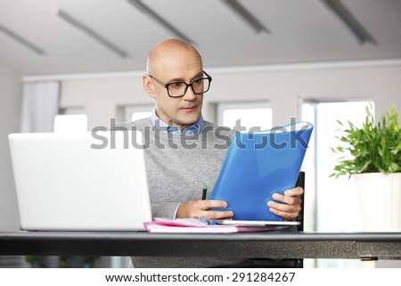 Portrait of financial director sitting at office in front of computer and working on business report.