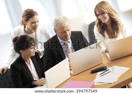 Portrait of group of business people sitting at office in front of laptop and working together on financial plan. Young officer getting business advice.