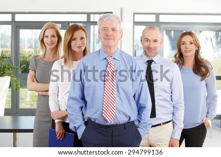Portrait of group of business people in row. Businesswomen and businessmen standing at office.