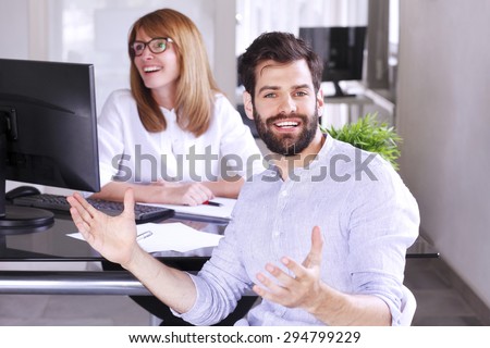 Businesswoman sitting at office desk and interviewing young professional man. Middle age professional woman sitting in front of computer and making successful business deal with young businessman.