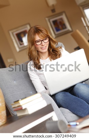 Portrait of female interior designer working at home. Casual businesswoman sitting on armchair at home while working on her computer. Small business.