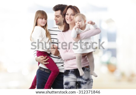Portrait of happy young family with cute girls standing in living room.