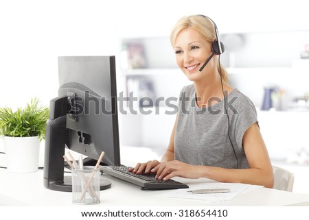 Portrait of a beautiful customer representative with headset smiling during a telephone conversation.