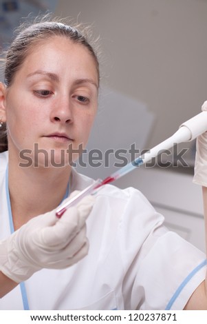 Woman taking sample from test tube with micro pipette