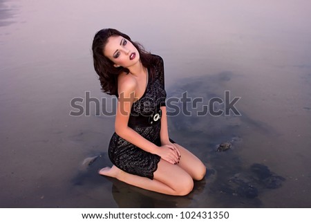 Beautiful young sexy fashion model in dress in  the sea