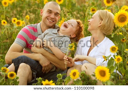 happy family having fun in the field of sunflowers. Father hugs his son. Mother holding sunflower. outdoor shot