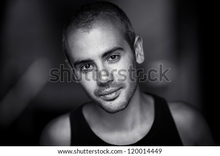 Fine art close-up black and white portrait of beautiful young man's face against black background, collage of two photos