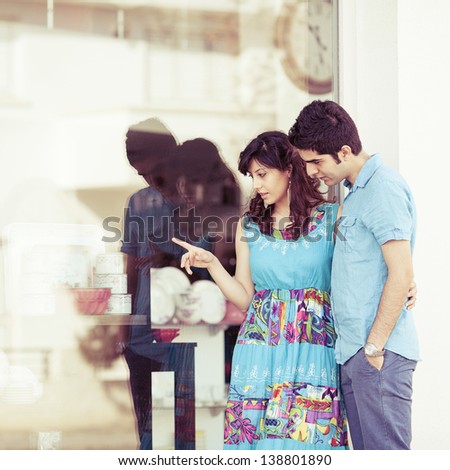 young couple looking into shop window and discussing