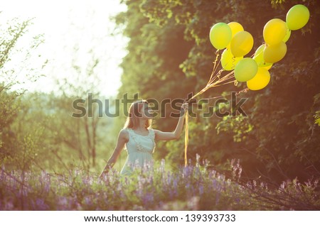 young beautiful girl with baloons in the field of flowers