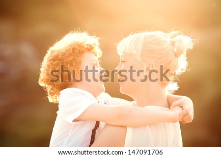 happy mum and her red head son having fun together outside on the beach, close up