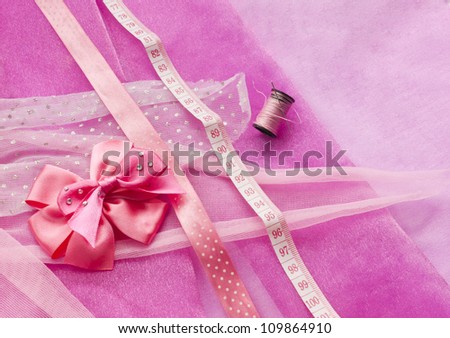 Sewing something pink. Pink cloth, ribbons and bows, ready to start making a dress.