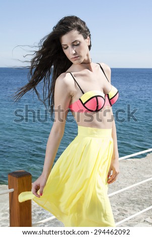 Women near sea in neon bikini and yelow skirt