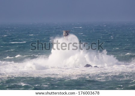 Huge waves crashing Longships Lighthouse photographed from Lands End Cornwall England UK