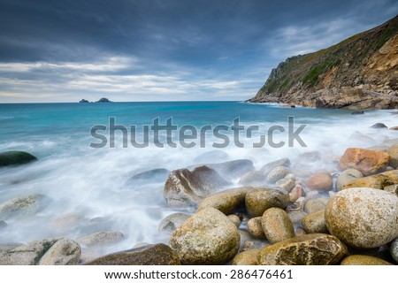 Boulder covered beach at Porth Nanven at the end of Cot Valley with the Brisons on the Horizon, Cornwall England UK Europe
