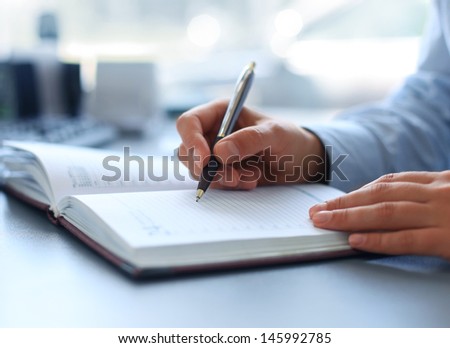 Businesswoman makes a note in notebook.