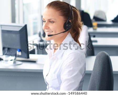 Beautiful young female call center operator with headset in office