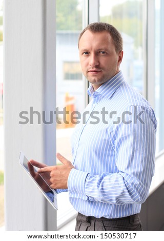 Closeup of a young business man at his office and using his modern tablet pc to do his work