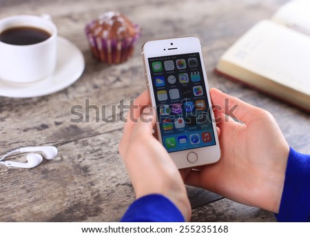 MINSK, BELARUS - February 22, 2015: Woman holding brand new white Apple iPhone 5S. Social media are trending and both business as consumer are using it for information sharing and networking.
