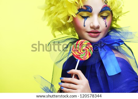 Girl with with creative make-up holds lollipop. Doll style.