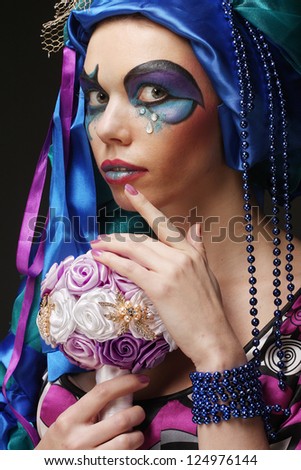 Young woman with creative make up holding a bouquet of jewelry