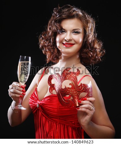 Woman in red dress at the carnival with mask, champagne flute and bengal light