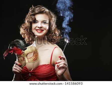 Woman in red dress at the carnival with mask, champagne flute and bengal light
