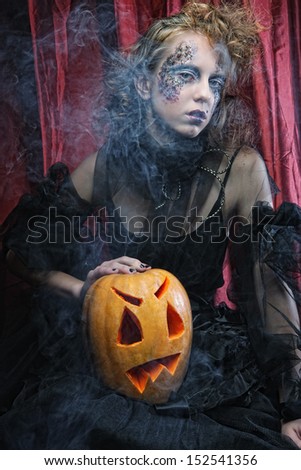 Halloween witch with  carved pumpkin over red  background.