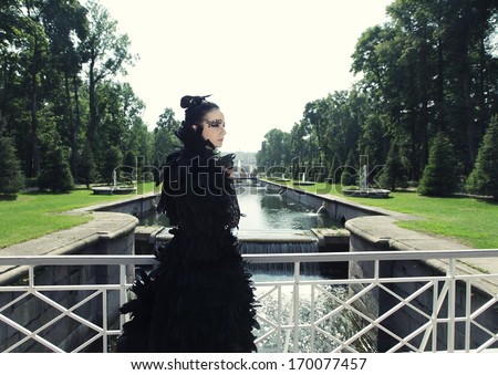 Dark princess on the bridge. Fashion model posing in summer park.