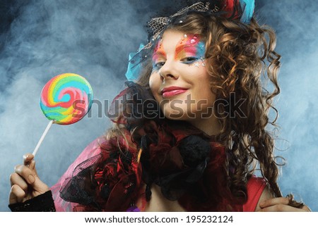Girl with with creative make-up holds lollipop. Doll style. Studio shot.