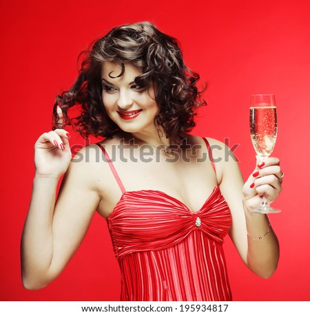 A beautiful happy woman in a red dress holding a glass of sparkling wine or Champagne.