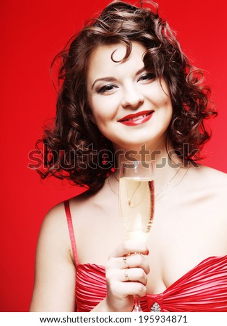 A beautiful happy woman in a red dress holding a glass of sparkling wine or Champagne.
